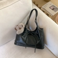 Minimalist black faux leather underarm bag with bow detail and plush charm on a sofa - Black without Pendant