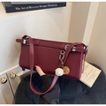 Close-up of a burgundy minimalist rectangular bag with a dual-tone fur ball pendant accessory - Burgundy