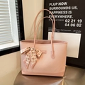 Pink quilted tote bag with bow scarf detail shown in a stylish urban setting - Pink