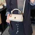 Minimalist beige leather handbag with star charm and gold lock shown in a lifestyle setting - Off White