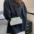 Elegante weiße Perlen-Schalentasche mit Perlengriff und Metallkette auf schwarzem Anzug - Weiß