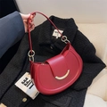Chic red saddle shoulder bag with golden crescent clasp on black tweed jacket - Red