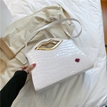 White faux leather crossbody bag with crocodile texture and gold lip shaped handle - White