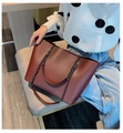 Deep burgundy large tote bag with leather straps and metal chain worn by a female model - Dark Brown