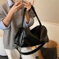 Minimalist black leather tote bag with wide strap shown in a stylish mirror selfie - Black