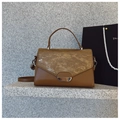 Brown leather handbag with textured flap and metallic clasp on a stone surface - Brown
