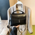 Retro black leather handbag with white contrast stitching and a woven shoulder strap - Black