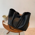 Detail of black large tote bag showing textured lychee leather and long shoulder straps - Black