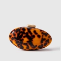Macro detail of tortoiseshell acrylic clutch bag with golden pebble clasp - Amber