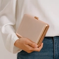 Detail of rose gold hard shell evening clutch with vertical metallic texture and clasp - Gold