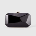 Detalle de bolso de mano rígido negro con facetas geométricas y cierre de metal dorado - Negro