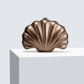 Macro detail of bronze shell evening bag with vertical fan texture and metal clasp - Coffee