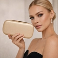 Elegante borsa pochette rigida dorata con finitura metallica e chiusura tenuta da modella - Oro