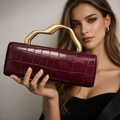 Detail of burgundy crocodile-embossed leather handbag with sculptural gold metal handle - Burgundy