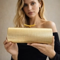 Detailed close-up of golden crocodile pattern clutch with luxury metal buckle - Gold
