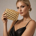 Pochette de soirée dorée en métal avec texture matelassée tenue par un mannequin chic - Doré