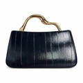Detailed view of the dark textured patent leather and wavy gold metal handle on handbag - Black