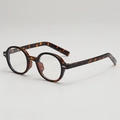 Monture de lunettes ovale rétro en écaille avec accents métalliques sur fond gris clair - Monture Écaille Lentille Claire