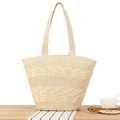 Stroh-Tragetasche in hellem Beige mit Wellenstruktur und langen Schulterriemen auf Holztisch - Beige