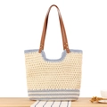 Borsa tote intrecciata beige a righe azzurre con manici in pelle su tavolo di legno - Striscia Blu