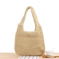 Handwoven straw tote bag in light khaki color with integrated handles on wooden surface - Beige