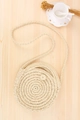 Elegant cream white hand-woven round crossbody bag with rustic wooden background - Beige