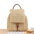 Forest-style beige straw woven backpack with brown leather handle on a wooden table - Beige