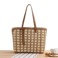 Beige and brown checkered woven tote bag with long brown leather handles on a wooden table - Tan