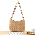 Woven straw shoulder bag in natural tan with amber acrylic chain strap on wooden surface - Camel