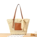 Stroh-Stoffbeutel mit braunem Lederpatch und beiger Spitzenschleife auf Holzplatte - Beige mit Spitzenband