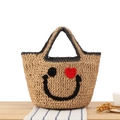 Handmade woven straw tote bag with smiling face and red heart eye in natural beige - Black Border