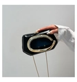 Macro view of geometric black patent leather bag with signature gold C-shaped metal handle - Black
