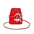 Macro detail of red lychee leather bucket bag with pearl bow and silver heart charm - Red