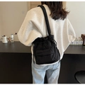 Detail of black nylon drawstring bucket bag showing front flap pocket and wide shoulder strap - Black