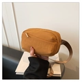 Detail of a ginger yellow nylon waist bag showing its textured fabric and front zipper - Yellow Brown