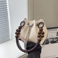 Creamy white PU leather bucket bag with wooden bead handle and metal tassel charm - White