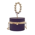 Close-up of purple cylindrical evening bag with gold beaded handle and metal chain - Purple