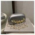 Close-up of silver evening bag featuring gold wavy metal trim and snake chain strap - Silver
