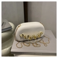Close-up of white acrylic evening bag with wave gold metal decor and chain strap - White