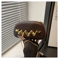 Detail view of brown acrylic clutch bag with gold wave handle and metal chain strap - Brown