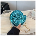 Metallic blue shell clutch bag with gold chain strap held against a silk backdrop - Blue