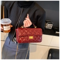 Detail of red patent leather quilted handbag with gold clasp and elegant chain strap - Red