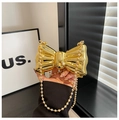 Close-up of golden bow-shaped metal evening bag with glossy finish and beaded chain strap - Gold Ball Chain Style