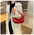 Detalle de un bolso de media luna rojo metálico brillante llevado por una modelo elegante - Rojo