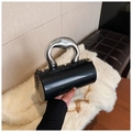 Detail view of black cylindrical evening bag with silver wavy metal handle and gold chain - Black