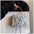 Detail van zilveren acryl clutch tas met vloeiende golftextuur en metalen ringhandvat - Golvend Zilver