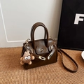 Klassische dunkelbraune Handtasche mit Goldschloss und niedlichem Plüschanhänger - Kaffeebraun mit Anhänger