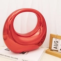 Macro detail of glossy red crescent moon acrylic bag handle on minimalist art books - Red