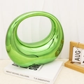 Detail of emerald green hollow oval ring ornament with glossy metallic finish on books - Green