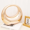 Close-up of modern gold mirrored ring sculpture on white book for home decor - Champagne